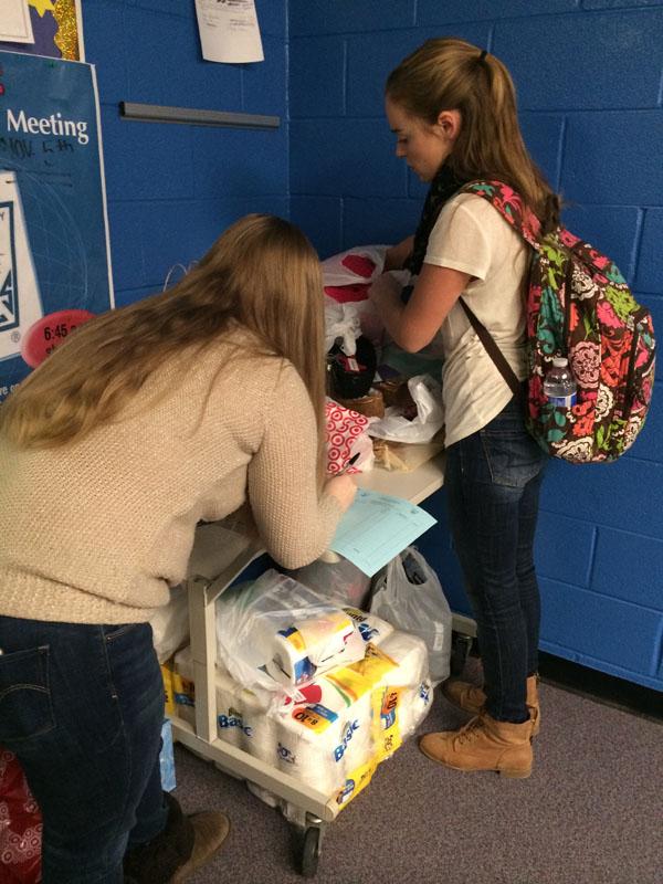 NHS+president+Haley+Zynda+signs+off+a+students+hours+sheet+as+they+turn+in+their+donations+to+the+NHS+office.