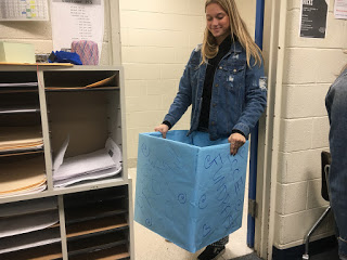 Project Unify club member Anna Lippert puts Fundraising box in classroom.