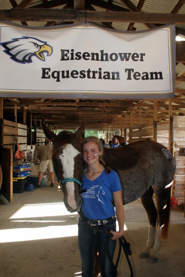 Finishing up the horse show, sophomore Kendall Westgate stands with her horse Paisley under a sign.