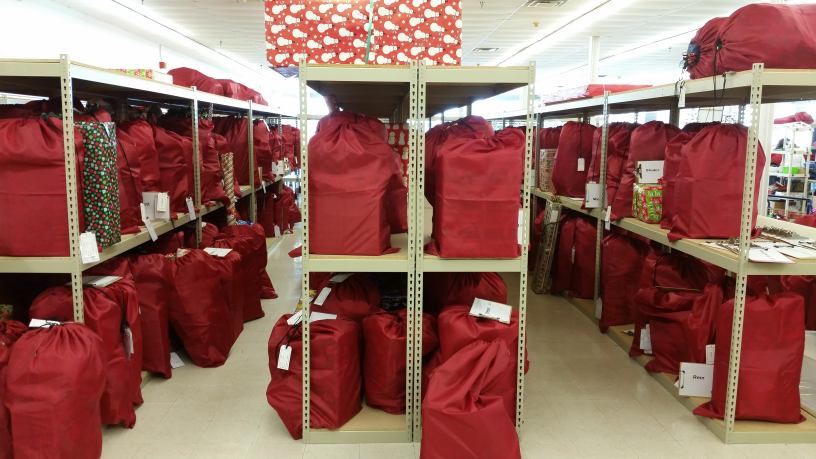 Lined up in rows, the big, red bags are filled with many gifts that are ready to be wrapped by the volunteers.