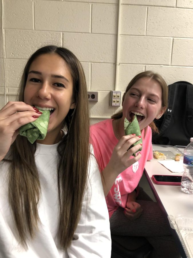 Taking a bite of the Turkey Boom Club Wrap, seniors Gabriella Gjonaj and Ava Kaspari taste test a school lunch. 