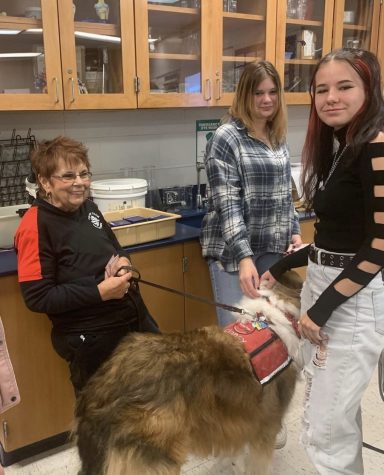 Juniors Hannah Ciolac and Courtney Witherow pet Clancy, one of the therapy dogs brought in. “I think it was really welcoming and chill which makes me want to come back,” Ciolac said. The club hopes to host the dogs again in the future, next time bringing them into lunch as a way to spread awareness and promote the club.    PHOTO CREDIT: @eaglesoar_ on Instagram