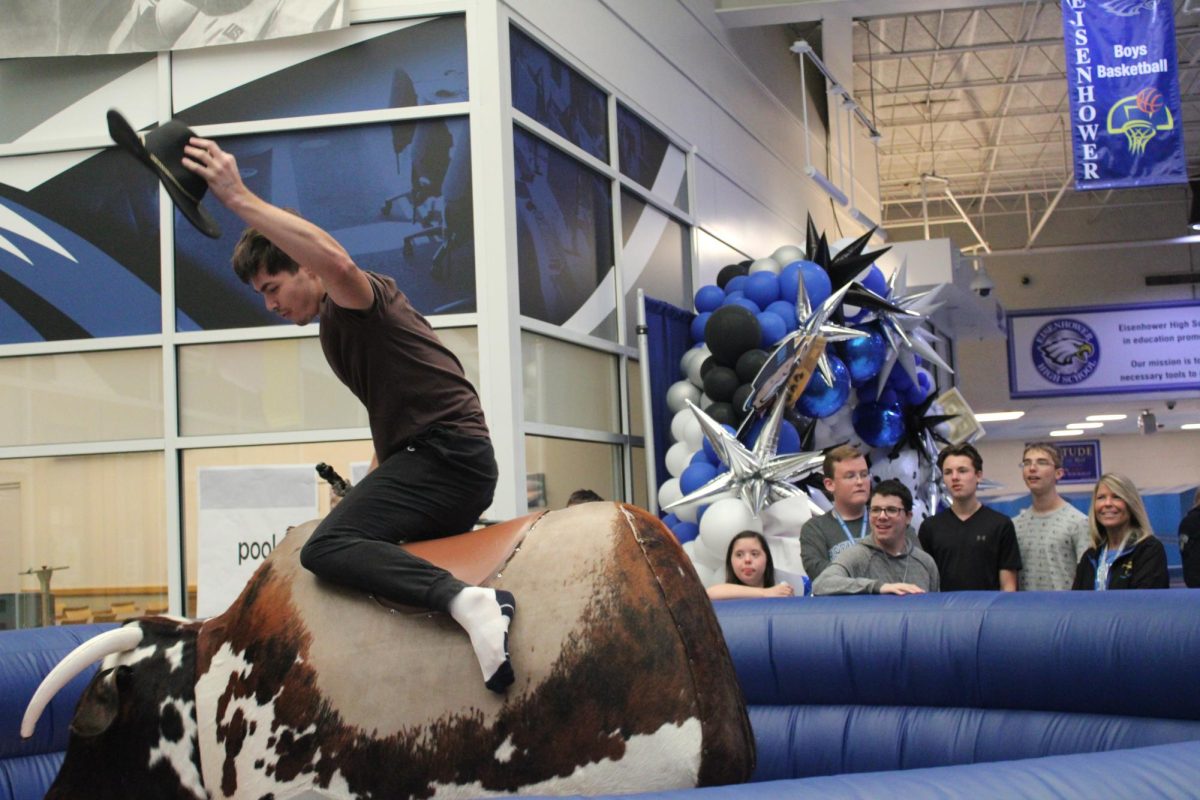 Western day fun. During A lunch, students corral in the commons and watch senior Justin Gjokai as he rides the mechanical bull. Gjokaj’s friends encouraged him to try the homecoming spirit week activity after he finished lunch. His favorite part of western day turned out to be riding the bull because “it was fun,” he said. 
