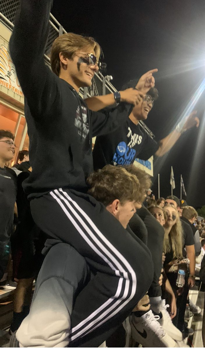 Get loud. During the Homecoming game senior Kenneth Vroom enjoys the view of the field from his friend’s shoulders. Vroom is a fan of football and attended every home game. “It was just kind of cool to see the school cop participating in school events, bringing everyone together,” Vroom said. 

