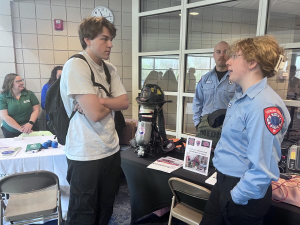 Career lingo. Talking to a Shelby Fire Department firefighter, senior Brody Shemanski attends the first school to work fair. Preparation began back in Nov, 2023. “I feel honored (to attend the fair),” Shemanski said. “There’s a lot of nice people here to talk to us.” 
