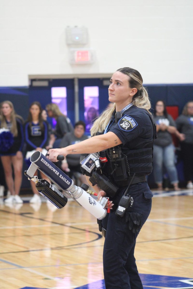 WATCH OUT. Student resource officer Lauren Weiss carefully tests out a t-shirt launcher during the pep assembly for future football games. “I had fun, but I had to be careful too. I didn’t want to aim too high because it’s got a lot of kick to it,” Weiss said.