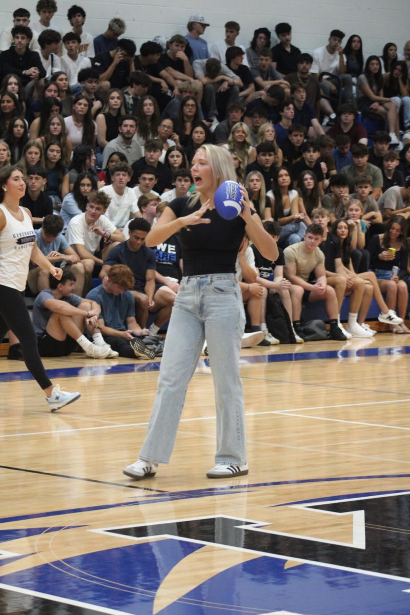 HUT, HUT. With football in hand, junior Ava Vanwambeke aims at her partner’s hula hoop during the pep assembly games.
