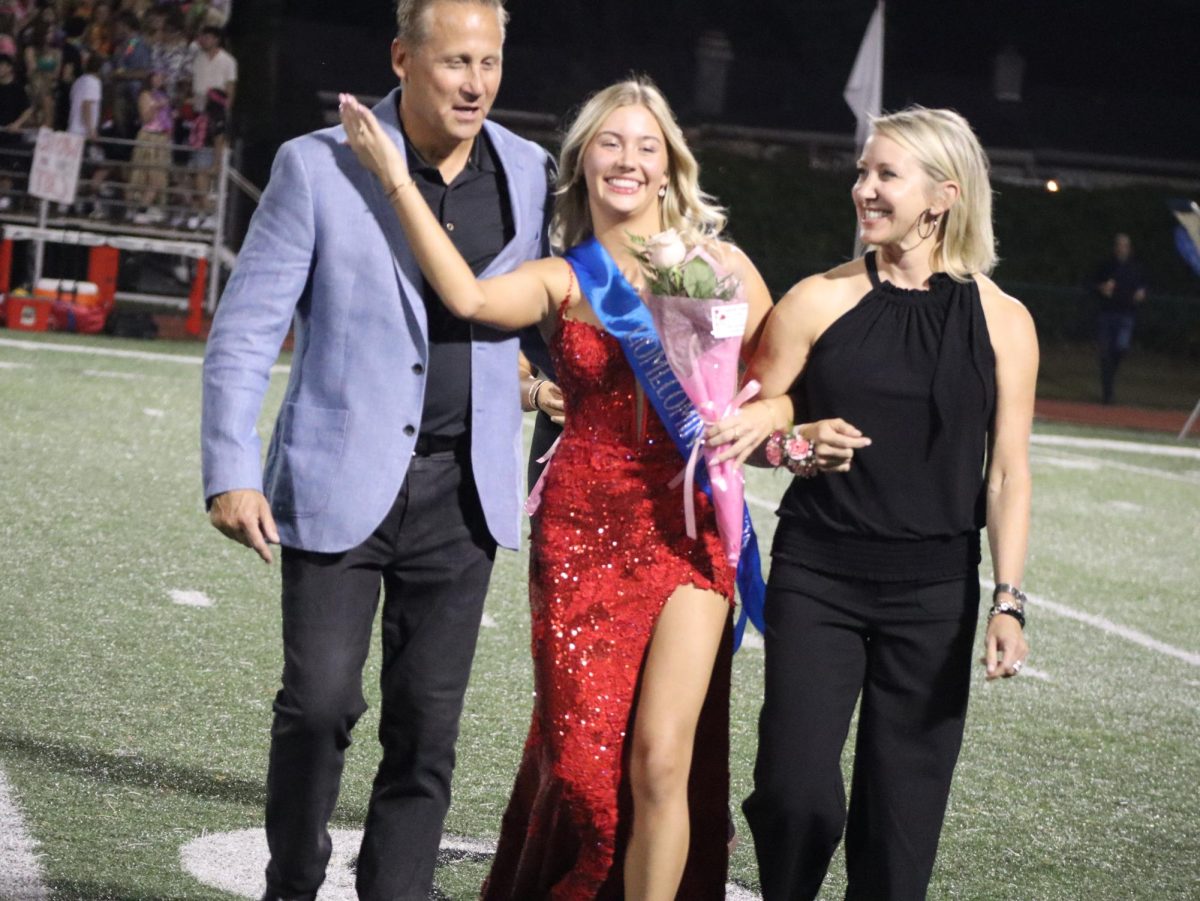 Feeling proud, senior Ava Skonieczny walks with her parents by her side during the homecoming game. Seniors had to vote with the choice of about 600 people to be placed on the homecoming court. “I did not expect to get placed on homecoming court. I felt really excited,” Skonieczny said.
