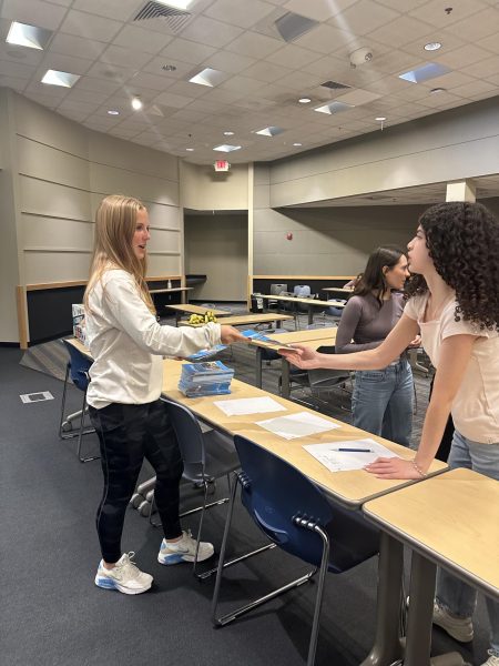 As new key club members arrive at the mixer on Tuesday, Oct. 8, junior key club secretary Sonja Peterson passes an information pamphlet to sophmore Maria Kaci. Since this is Peterson’s first year on the board it was her first time helping run the event. “It was really great to see all the new members and help them. I’m really looking forward to working with them this year and next year,” Peterson said.