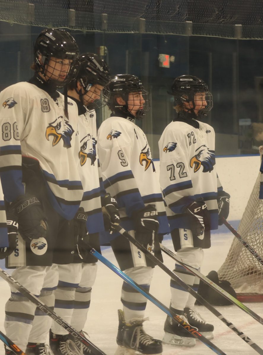 Weston Szudarek and other graduates huddle up together watching the introductions. With nerves taking over they stand there and acknowledge the event that's happening. "I was nervous, it was my first year of hockey but the seniors helped me through it and calmed me down." said Szudarek