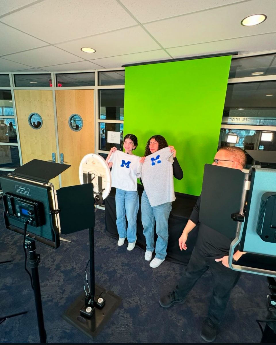 Sophomores Maria Kaci (left) and Reagan Kado (right) hold up their custom-made t-shirts for the camera at the Sophomore college fair.