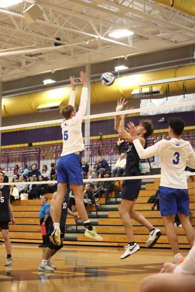 Reaching above the net, senior Kenneth Wright blocks Stoney Creek's hit. "The most I can do is just play and do things that are exciting," Wright said. "That might be the thing that gets one other person to come play." MHSAA incorporated mens volleyball into official high school sports.