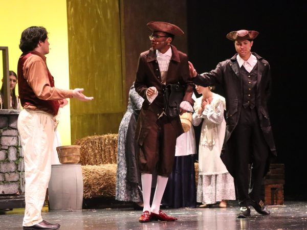 Students perform a scene from the fall play, 'The Legend of Sleepy Hollow'. Senior Camran Grayson takes on his role as Ichabod Crane, delivering lines about food during the festival scene.
