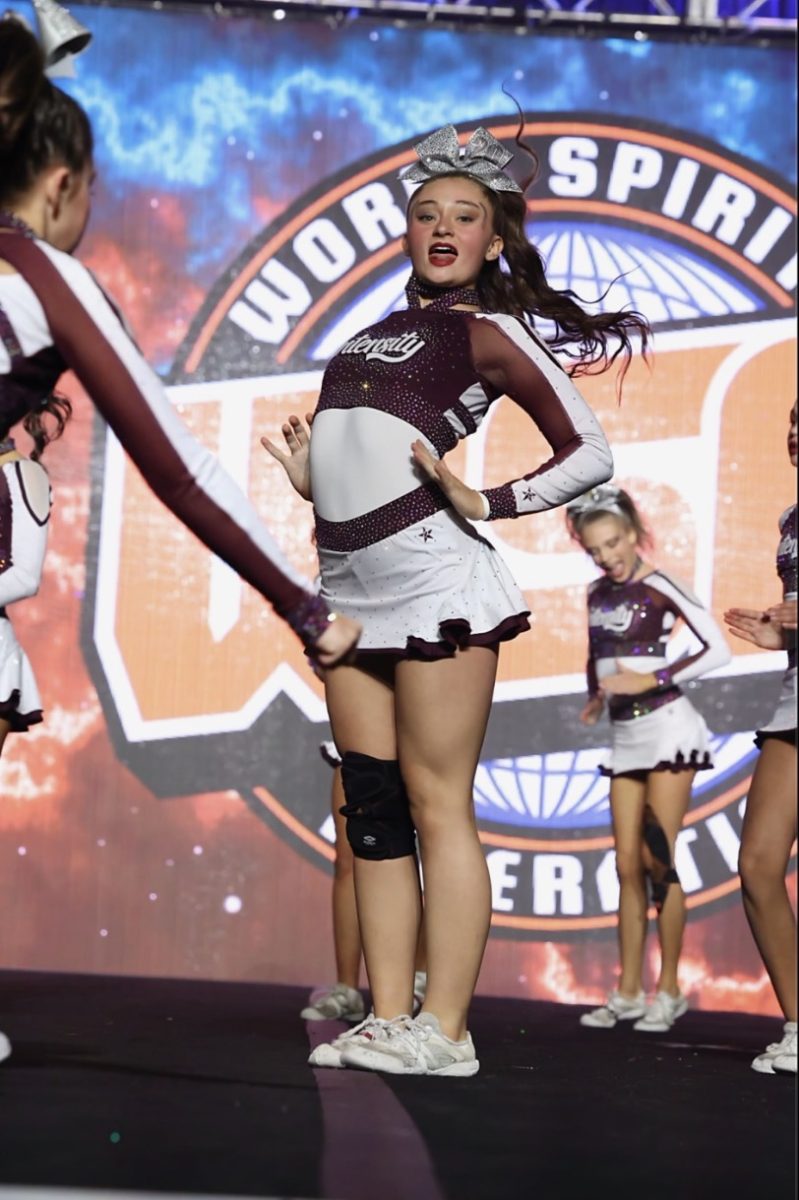 Up on stage with her teammates, junior Elianna Di Cesare is a base in their performance. The Intensity Elite team is at a competition at DeVos convention center in Grand Rapids where they won first place. “Under the lights, nerves turn into excitement, fear turns into focus, and I remember why I love this sport,” Di Cesare said. 
